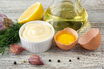 Mayonnaise sauce with garlic, egg, oil, lemon and herbs on wooden background