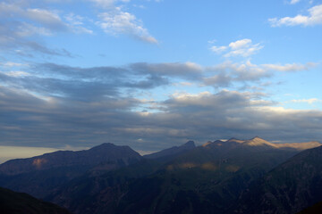 Naklejka na ściany i meble Silhouettes of mountains in the evening haze. Mountain ranges at sunset. Dusk.