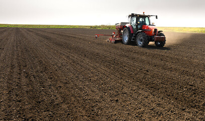 Obraz premium Farmer with tractor seeding crops at field