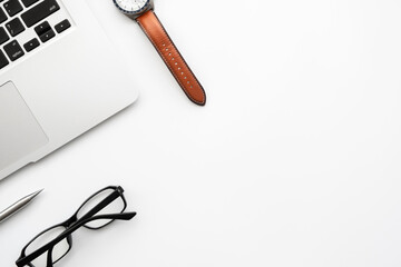 Wood office desk table with laptop computer, hand watch and office supplies. Top view with copy space, flat lay.