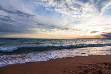 Beautiful sunset by the lake. Bright clouds are reflected in the water. Kyrgyzstan.