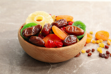 Wooden bowl with dried fruits on gray background