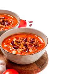 Chili con carne in a bowl on a white background close-up. Free space for text. Tex-mex food. Delicious spicy soup with red beans, peppers, tomatoes and minced meat. Copy space.