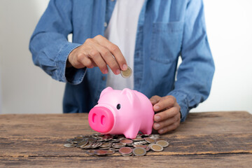 Closeup Man hand putting coin into a piggy bank, Concept of saving money and business investment.