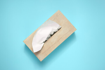 Wooden holder with paper tissues on light blue background, top view