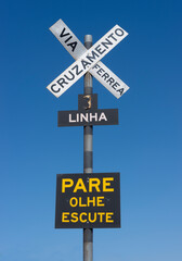 Fototapeta premium Railway crossing sign written in portuguese in Brazil in front of a blue sky background