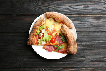 Slices of different delicious pizzas on black wooden table, top view