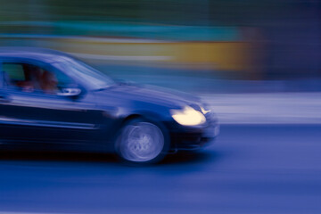 Fototapeta na wymiar Blurred blue car moving fast along night road 