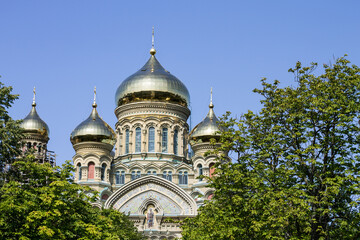 Fototapeta na wymiar Russian Orthodox Church in Liepaja in a sunny summer day, green trees at the front