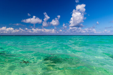 The ultramarine Caribbean sea with blue water and white clouds.