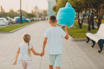 Happy children boy and girl eating blue cotton candy outdoors