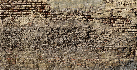 destroyed rough and ancient wall background with layers of gray cement and bricks from an abandoned building