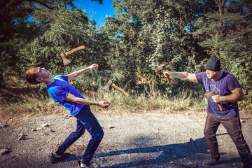 An angry and scary man in a hat throws axes at a man in the forest. The boy dodges the villain. The...