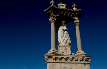 Fototapeta na wymiar A catholic statue lines the entrance to a bridge in the Spanish city of Valencia.