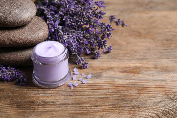 Fototapeta na wymiar Stones, jar of cream and lavender flowers on wooden table. Space for text