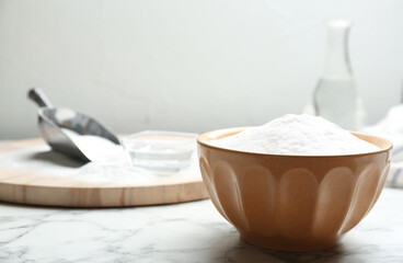 Fototapeta na wymiar Baking soda in bowl on white marble table. Space for text