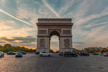 The sunset view of triumphal arch and traffic in Paris, France.
