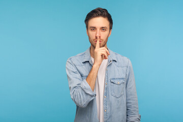 Shh, keep quiet, this is confidential! Portrait of handsome man in worker denim shirt showing...