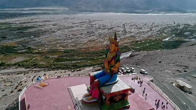 close up circling drone shot of an ancient budha statue situated in a remote mountain valley on a bright sunny day.