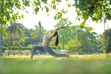 Young asian woman doing yoga under the tree in park