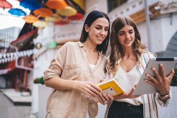 Prosperous female searching social publication on modern digital tablet and smiling on leisure, happy hipster girls browsing blog information during positive online networking via touch pad
