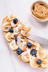Creamy peanut butter sandwich with banana and blueberry on grey marble tray. Breakfast. Selective focus