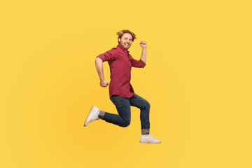 Enthusiastic happy lively guy in casual outfit jumping high trampoline, running fast quickly in air, hurry for sale. Life people energy concept. full length studio shot isolated on yellow background