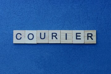 gray word courier in small square wooden letters with black font on a blue background