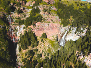 Aerial view of waterfall in the middle of the mountain surrounded by trees