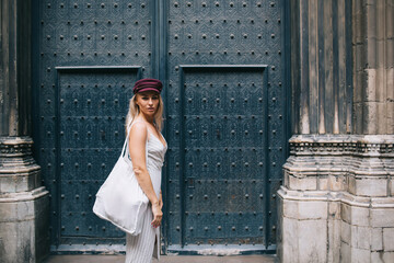 Half length portrait of female traveller with stylish eco bag posing near architecture with ancient...
