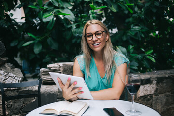 Portrait of cheerful female journalist 30s with digital tablet in hand smiling at camera during...