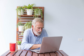 Senior retirement man is working with his laptop at home feeling unhappy