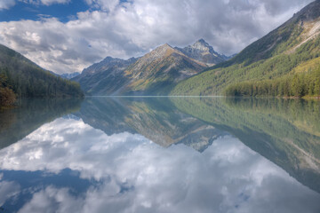 Mountain lake and high mountain. Mountains and clouds are reflected in the lake. Selective focus on the mountain. Soft focus.