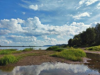 coastal landscape with green shore against blue cloudy sky