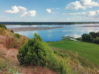 Obraz premium mountainside on the background of a river with a sandy island and a blue sky with clouds