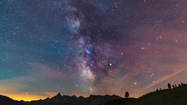 Time Lapse: the Milky way galaxy and stars rotation over the majestic Italian French Alps. Night sky on beautiful rocky mountains. Airplane traffic and satellites orbiting.