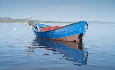 Fototapeta premium Boat in the water. Fishing boat in the calm waters of the pond of santa caterina in southern sardinia