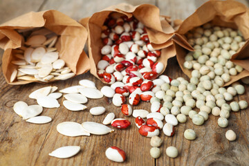 Different vegetable seeds on wooden table, closeup