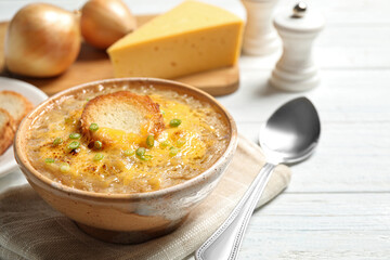 Tasty homemade french onion soup served on white wooden table