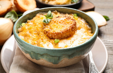 Tasty homemade French onion soup on wooden table, closeup
