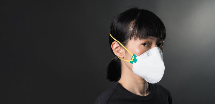 Middle Aged Of Asia Chinese Woman Wearing Medical N95 Mask That Help Prevent Or Protect Her From Coronavirus Or Covid-19 Pandemic And Safety From Air Pollution. And Copy Space