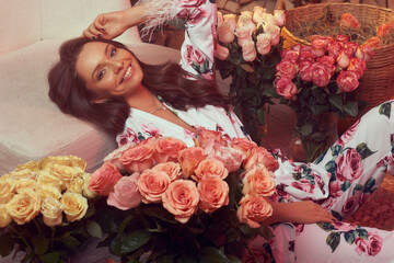 Young woman in floral design pyjamas costume sitting at wooden floor at home with lots of roses....