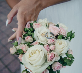 bride's hand with an elegant wedding ring with white gold diamonds on a bouquet of their peonies