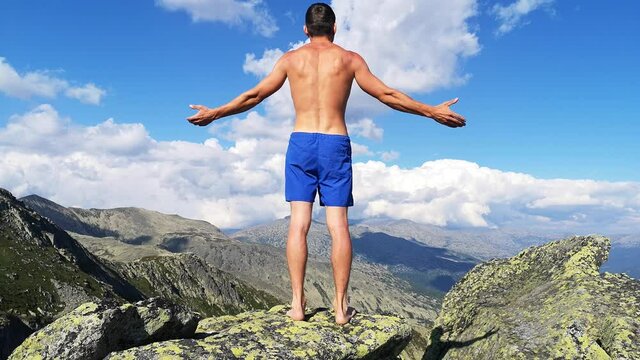 man stands on top of a mountain with open hands. at the top of the mountain, a man with his arms spread wide.