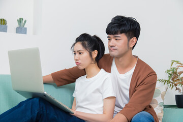 Fototapeta premium Asian woman and man working on laptop at home and thinking.