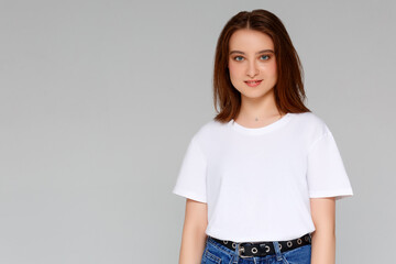 Close up portrait of smiling young woman in white t-shirt looking at camera, isolated on gray background