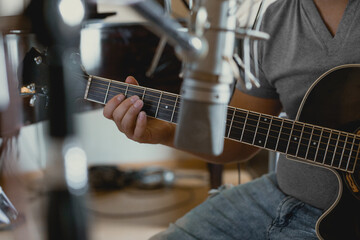 Close-up of musician's hand recording the sound of his acoustic guitar in a recording studio