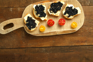 Sandwiches with black caviar on a wooden board on a wooden table, copy place.
