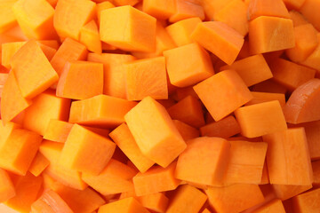 Cubes of fresh ripe carrots as background, top view