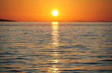 Beautiful orange sundown above wavy blue sea water